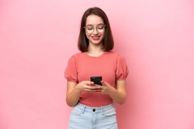Pembe arka planda izole edilmiş genç Ukraynalı kadın cep telefonuyla mesaj gönderiyor.