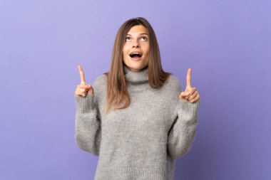 Mor arka planda izole edilmiş genç Slovak kadın şaşırmış ve işaret ediyor