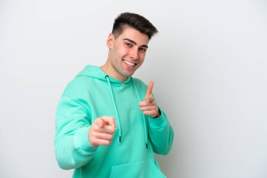 Beyaz arka planda izole edilmiş genç beyaz adam şaşırmış ve ön tarafı işaret ediyor.