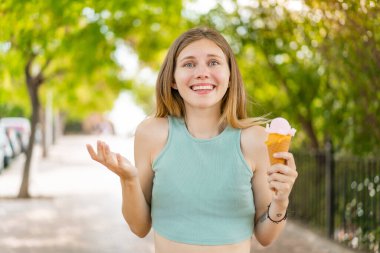 Açık havada kornet dondurmalı sarışın güzel bir kadın ve şok olmuş bir yüz ifadesi var.