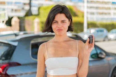 Genç, güzel, Bulgar bir kadın elinde arabanın anahtarlarını tutarken üzgün bir ifadeyle.