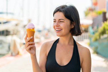 Açık havada kornet dondurması olan genç, güzel bir Bulgar kadın, neşeli bir ifadeyle.