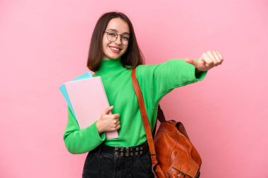 Pembe arka planda izole edilmiş genç Ukraynalı bir kadın baş parmak hareketi yapıyor.