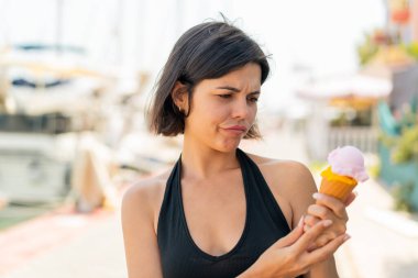 Açık havada kornet dondurması olan genç, güzel Bulgar kadın hüzünlü bir ifadeyle.