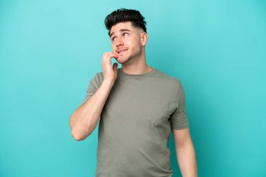 Mavi arka planda izole edilmiş genç beyaz adam biraz gergin.