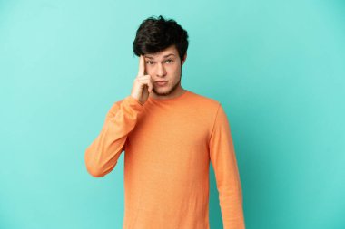 Genç Rus adam mavi arka planda bir fikir düşünerek izole edildi.