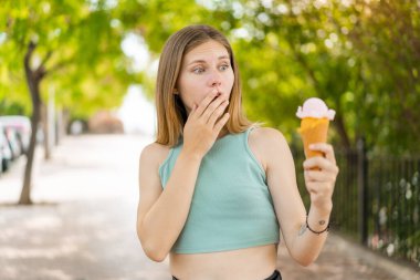 Açık havada kornet dondurması olan sarışın güzel bir kadın. Şaşırmış ve şok olmuş bir yüz ifadesi var.