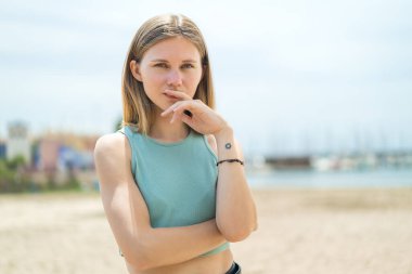 Açık havada düşünen genç sarışın kadın.