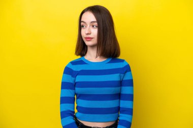 Sarı arka planda izole edilmiş genç Ukraynalı kadın yan tarafa bakıyor.