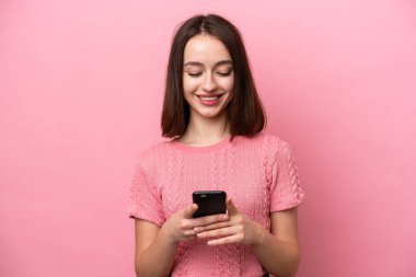 Pembe arka planda izole edilmiş genç Ukraynalı kadın cep telefonuyla mesaj ya da e-posta gönderiyor.