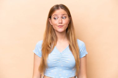 Beyazlı genç bir kadın bej arka planda izole edilmiş. Şüpheli hareketler yapıyor.