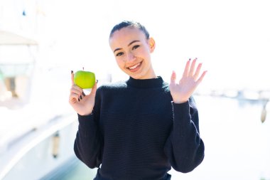Dışarıda elmalı genç Faslı kız mutlu bir ifadeyle selamlıyor.