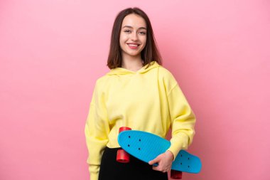 Young Ukrainian woman isolated on pink background with a skate