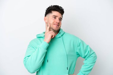 Beyaz arka planda izole edilmiş genç beyaz adam yukarı bakarken bir fikir düşünüyor.