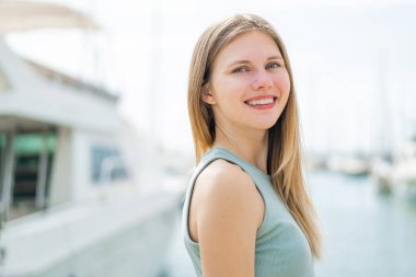 Açık havada genç sarışın bir kadın Neşeli bir ifadeyle