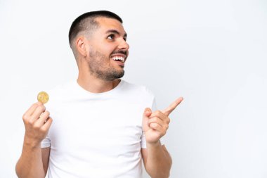 Beyaz arka planda izole edilmiş bitcoin tutan genç beyaz bir adam çözümü fark etmek için parmağını kaldırıyor.