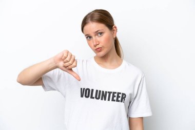 Beyaz arka planda izole edilmiş genç gönüllü kadın, olumsuz ifadeyle baş parmağını aşağı gösteriyor.