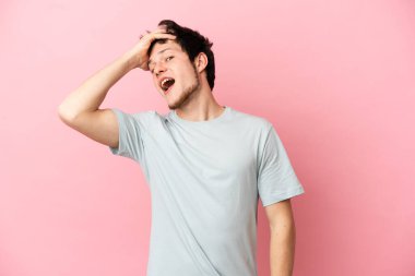 Pembe arka planda izole edilmiş genç bir Rus yan tarafa bakarken sürpriz jest yapıyor.