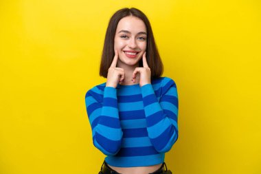 Sarı arka planda izole edilmiş genç Ukraynalı kadın mutlu ve hoş bir ifadeyle gülümsüyor.