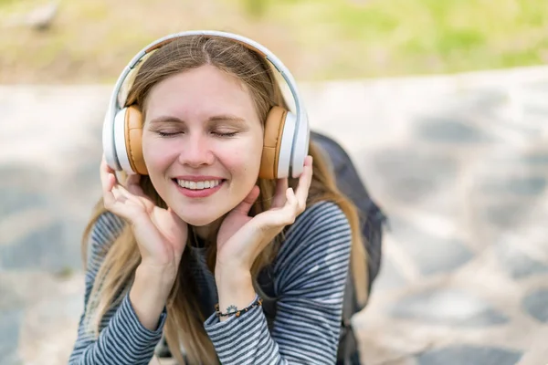 Açık havada müzik dinleyen genç sarışın kadın.