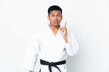 Beyaz arka planda karate yapan genç Ekvadorlu bir adam çözümü bulmak için parmağını kaldırıyor.