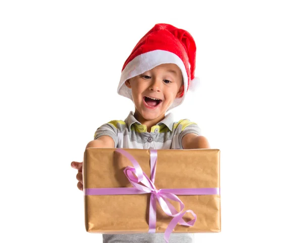 Enfant avec chapeau de Noël donnant un grand cadeau jaune — Photo