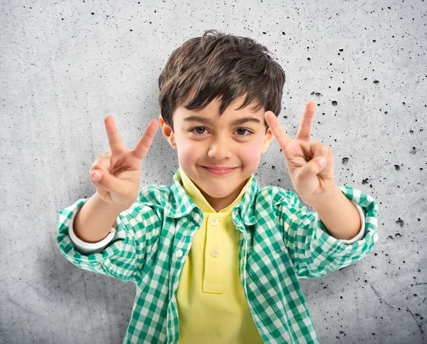 Junge macht ein Siegeszeichen vor weißem Hintergrund — Stockfoto