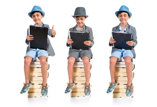 Cute boy sitting on books with thumb up — Stock Photo, Image