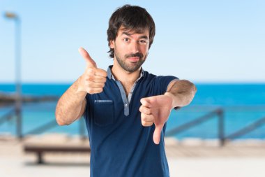 Beyaz arka plan üzerinde kötü bir sinyal yapan erkek