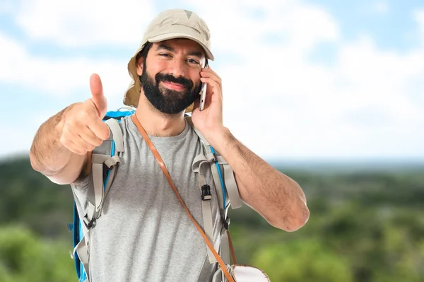 Backpacker spricht mit Handy über weißem Hintergrund — Stockfoto