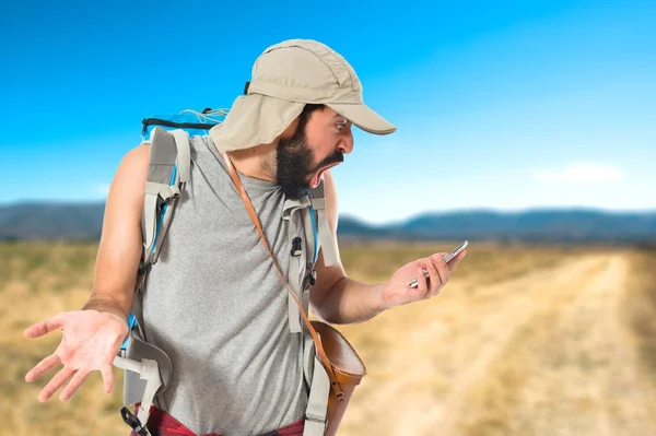 Förvånad backpacker pratar till mobila över vit bakgrund — Stockfoto