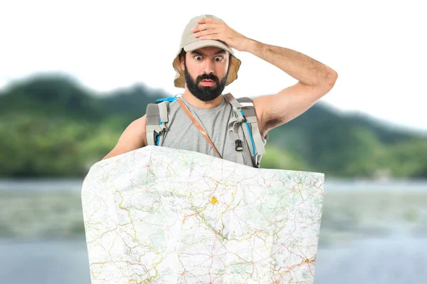 Zaino in spalla sorpreso con mappa su sfondo bianco — Foto Stock