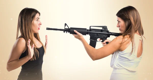 Woman pointing with a rifle at her sister — Stock Photo, Image