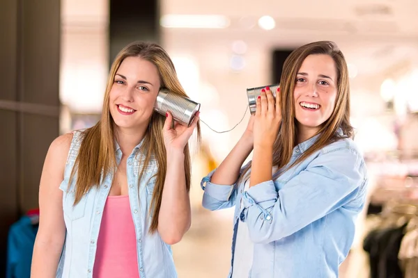 Amigos falando através de um telefone de lata sobre fundo branco — Fotografia de Stock