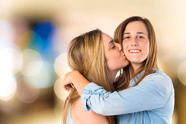 Chica dando beso a su hermana sobre fondo blanco — Foto de Stock