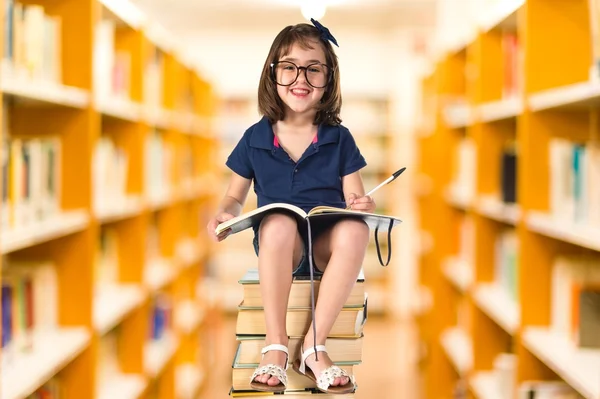 Dívka studuje na hromadě knih — Stock fotografie
