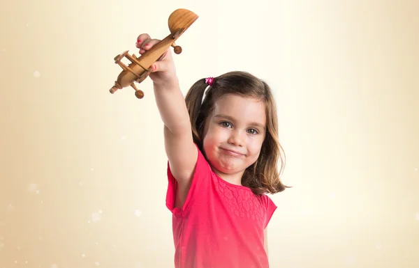 Flicka som håller en träleksak flygplan — Stockfoto