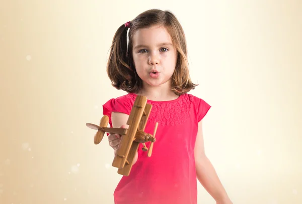 Girl holding a wooden toy airplane — Stock Photo, Image