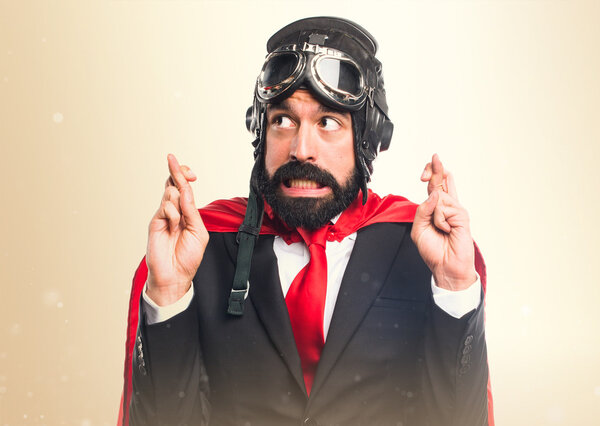 Super hero businessman with his fingers crossing