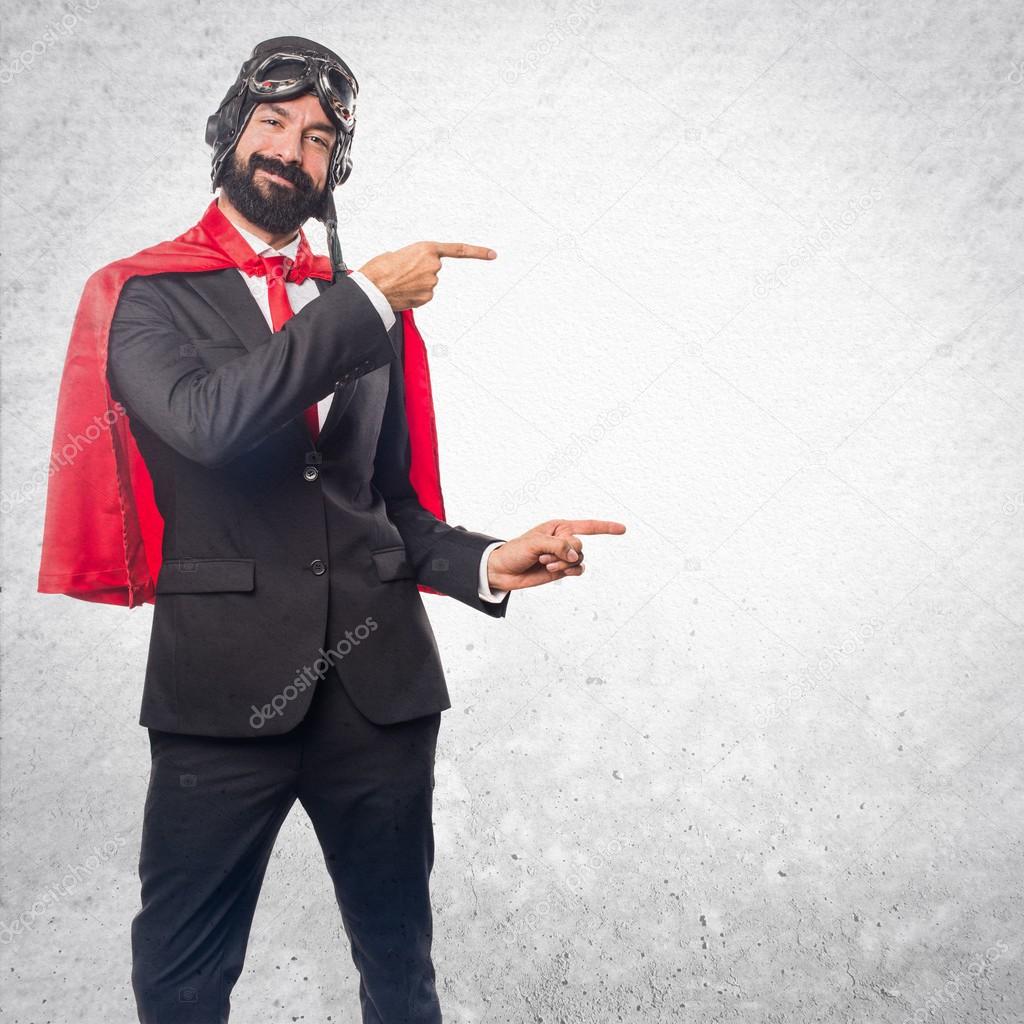 Super hero businessman pointing to the lateral