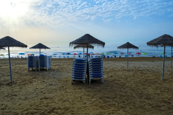 Puesta de sol en la playa con sombrillas — Foto de Stock