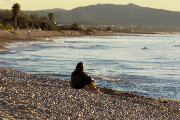 ผู้หญิงนั่งอยู่บนชายหาด — ภาพถ่ายสต็อก