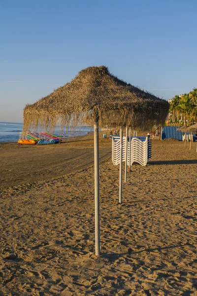 Puesta de sol en la playa y sombrillas — Foto de Stock