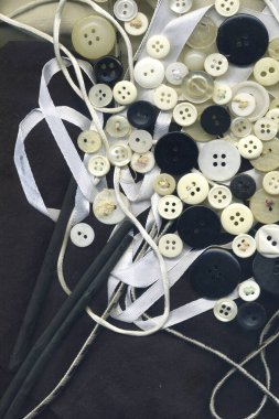 Düğmeler, beyaz ipek, iplik siyah beyaz görüntü. Tekstil aletleri ile çeşitli yedek düğme koleksiyonu. Kumaş dokusu duvar kağıdındaki dikiş düğmeleri çerçevesi