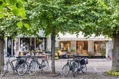 Hollanda 'nın Hanseatic kenti Elburg' daki küçük perakende mağazalarının önündeki kanalın yanına parketmiş bisikletler.