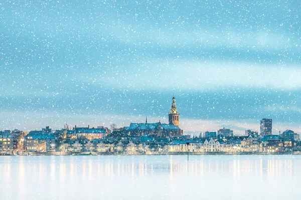 Hollanda 'nın Gelderland kentindeki Nijmegen şehrinin karlı ve buzlu kış manzarası ve önünde Waal nehri var.