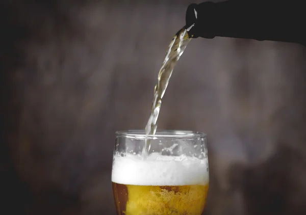 Beer with foam in glass. Bottle of beer