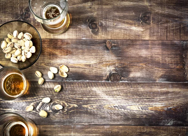 Cerveza, vaso, pistachos en una mesa de madera. Fondo de cerveza, parte superior —  Fotos de Stock