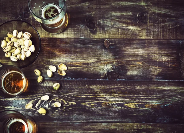 Cerveja, vidro, pistache em uma mesa de madeira. Fundo de cerveja, topo — Fotografia de Stock