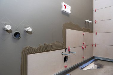 Banyo veya tuvaletin seramik fayanslarla yeniden inşası, seramik fayans kirpik seviyelendirme sistemi ile yapıştırıcı üzerinde konum